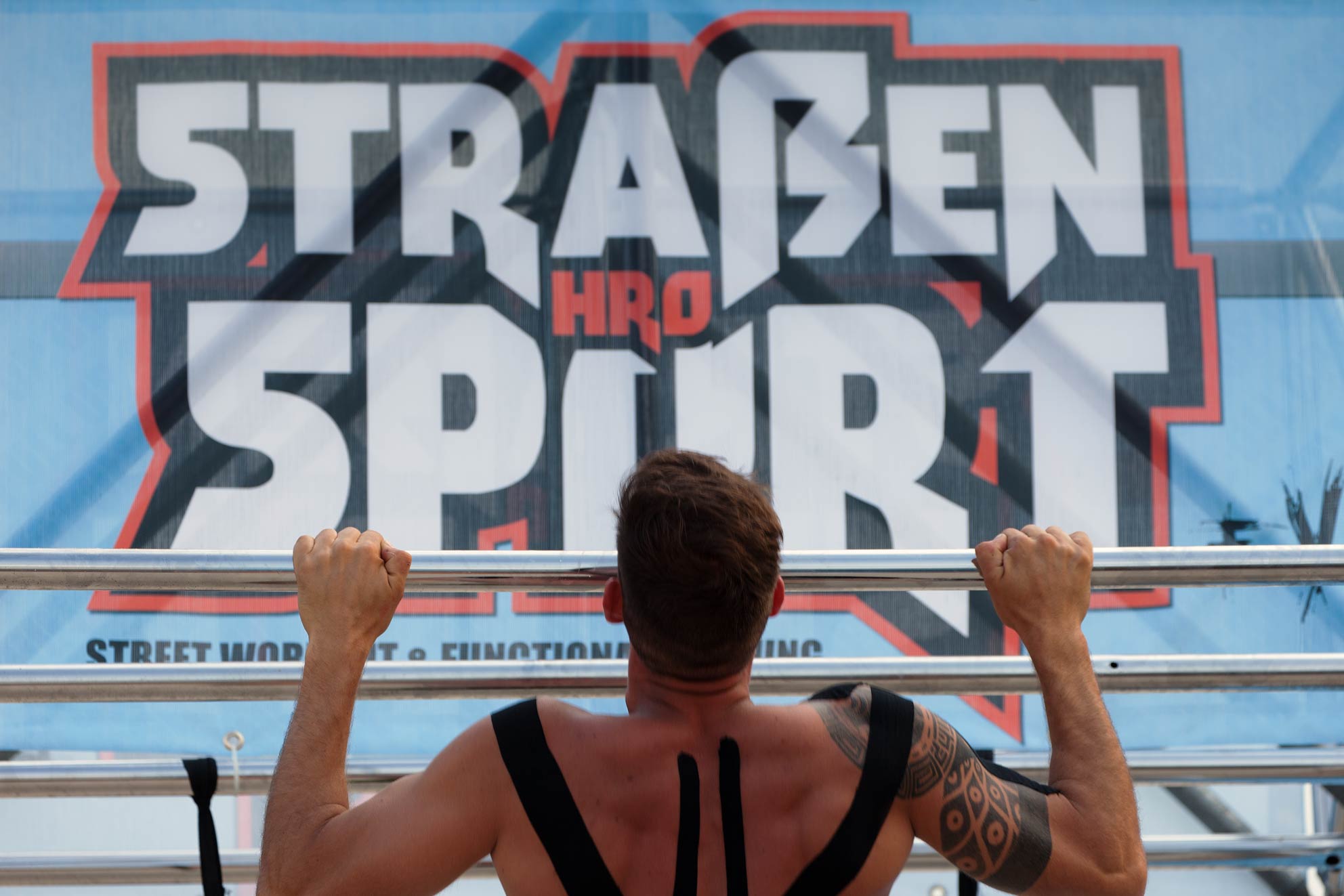 Klimmzug unter dem Banner von Straßensport Banner Straßensport. Darunter ein Mitglied, dass einen Klimmzug macht